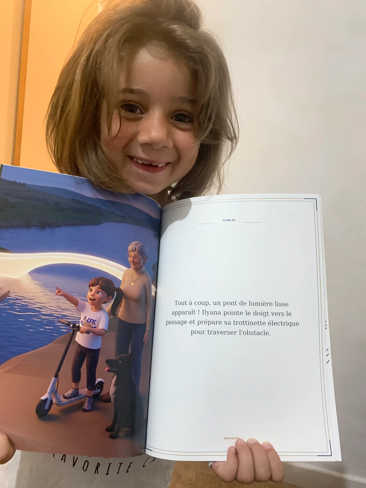 Une enfant sourit en présentant son livre ouvert sur une illustration et son récit